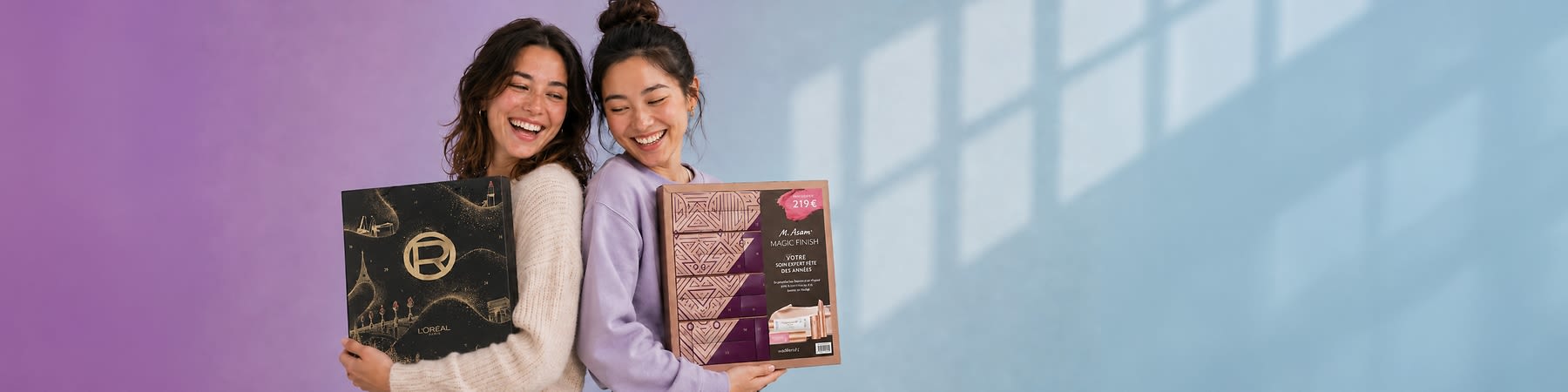 Zwei lächelnde Frauen Rücken an Rücken halten je eine Geschenkbox: links eine schwarze L’Oréal-Box mit goldenem Logo und goldenen Ornamenten, rechts eine rosa-braune M. Asam-Box mit Aufkleber „219 €“ und Text „Magic Finish“. Bild mithilfe von KI erstellt