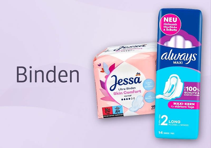 Zwei Packungen Damenbinden nebeneinander: links rosa-weiß verpackte Jessa Ultra-Binden Skin Comfort, rechts blaue Always Maxi-Packung mit Aufschrift „Maxi-Kern“ und Abbildung einer Binde, links daneben großer Schriftzug „Binden“