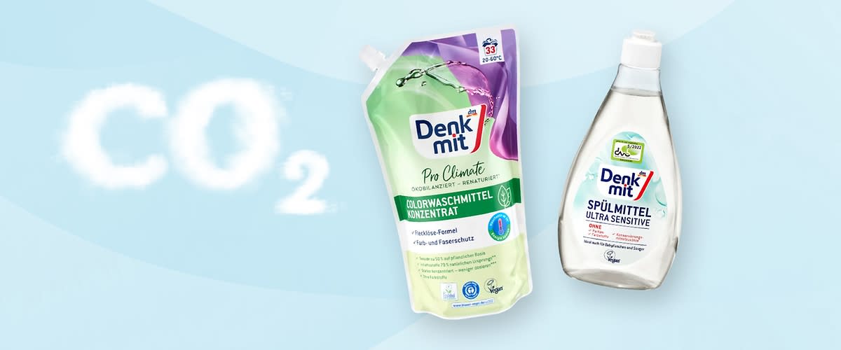 Eine Flasche Denkmit Spülmittel Ultra Sensitive und eine Packung Denkmit Pro Climate Colorwaschmittel Konzentrat auf hellblauem Hintergrund mit CO2-Schriftzug in Wolkenoptik