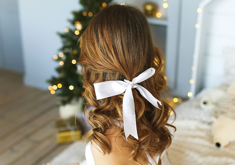 Frau mit festlicher Frisur und halboffenen Locken mit Schleife