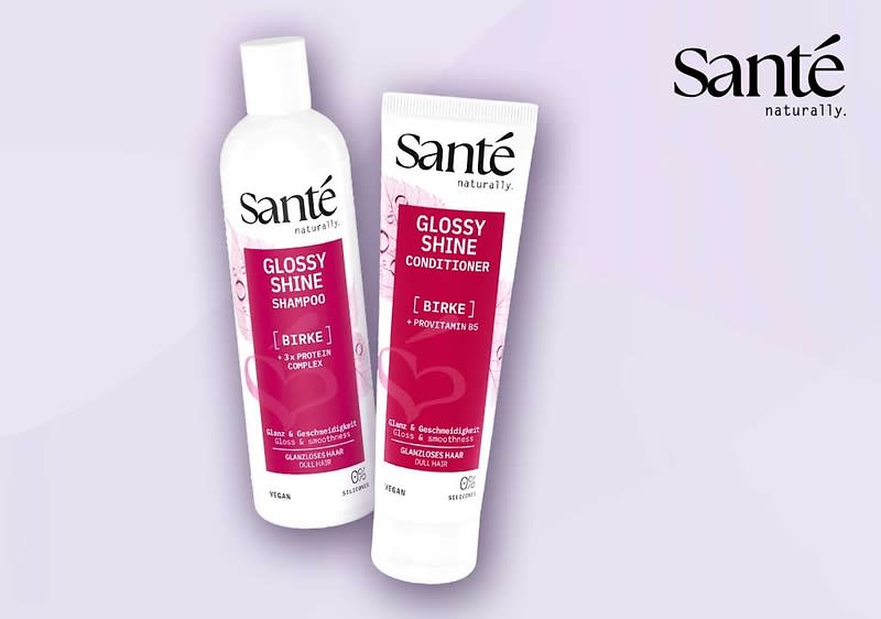 Zwei weiße Produktverpackungen der Marke Santé: links eine Flasche mit Aufschrift „Glossy Shine Shampoo“, rechts eine Tube mit Aufschrift „Glossy Shine Conditioner“ jeweils mit rotem Etikett und zusätzlichem Text „Birke“ sowie Markenlogo oben rechts im Bild