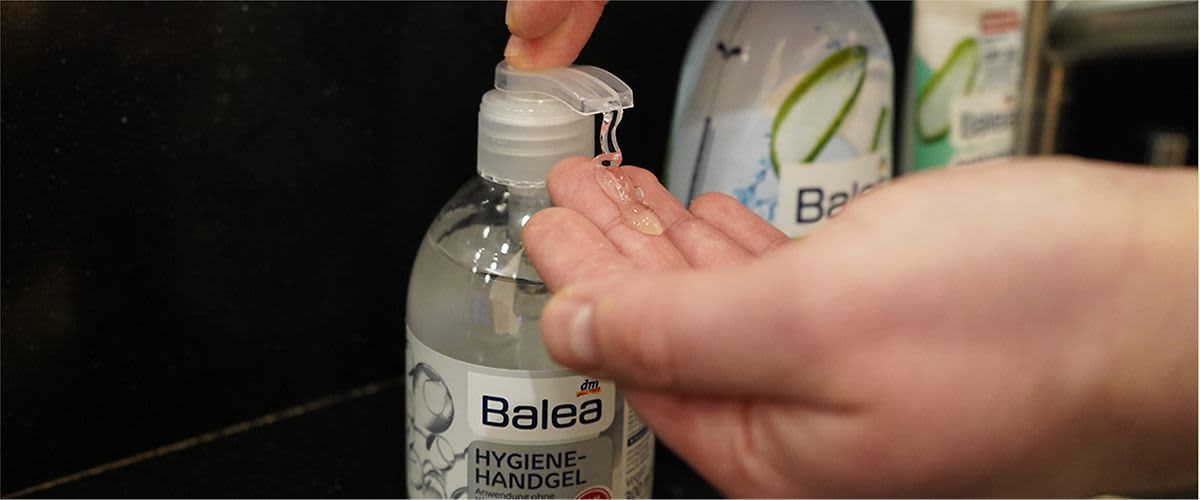 Eine Person drückt Hygiene-Handgel von Balea aus einer transparenten Flasche auf die Hand. Im Hintergrund sind weitere Balea-Produkte zu sehen.