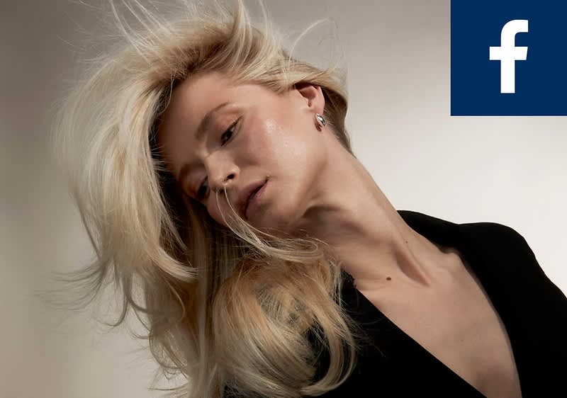 Eine Person mit langen, blonden Haaren trägt ein schwarzes Oberteil. Oben rechts ist das Facebook-Logo zu sehen.