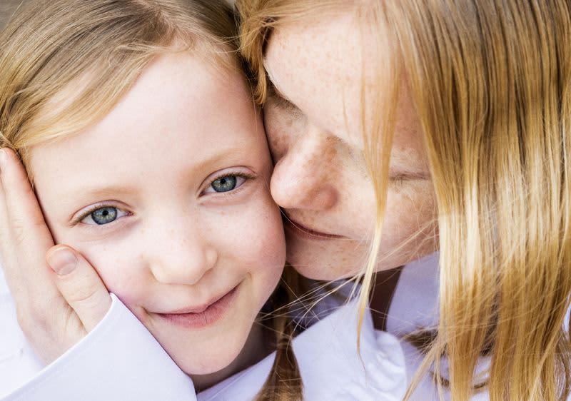 Žena koja grli i ljubi djevojčicu