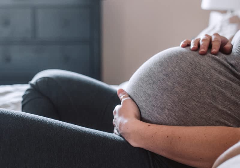 Žena drži svoj trudnički trbuh