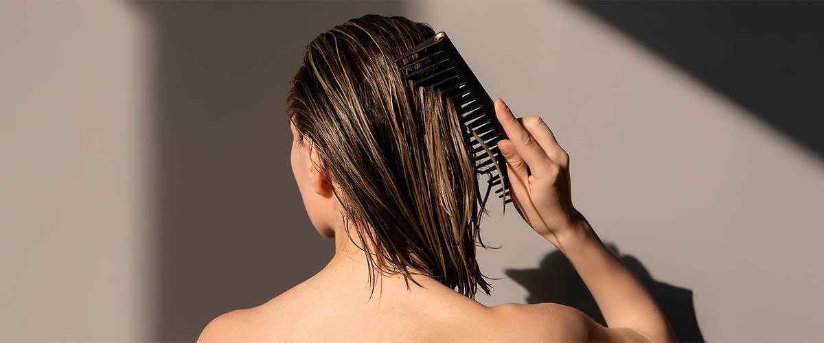 Žena češlja mokru kosu češljem