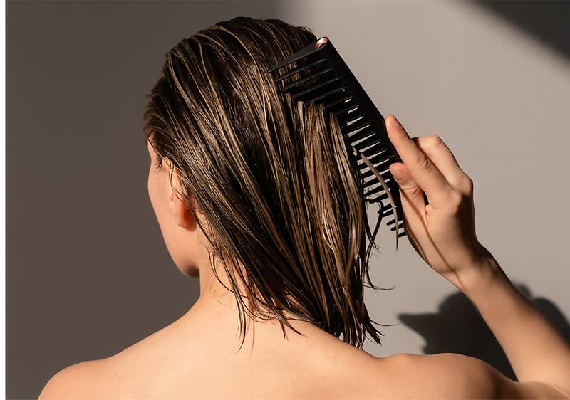 Žena češlja mokru kosu češljem