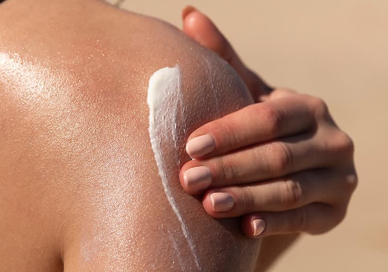 Žena se maže kremom po ramenu