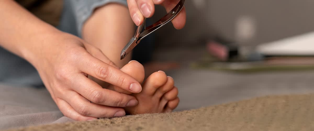 Žena reže nokte na svojim nogama