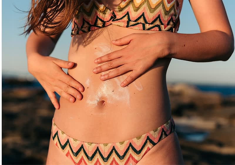 Žena u badiću se maže kremom za sunčanje