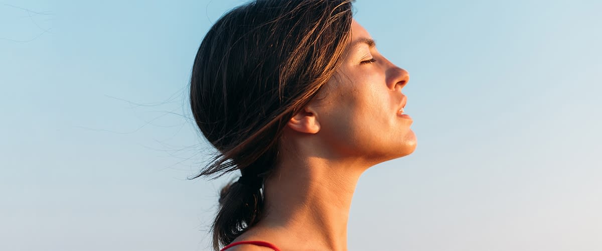 Žena zatvorenih očiju gleda u sunce
