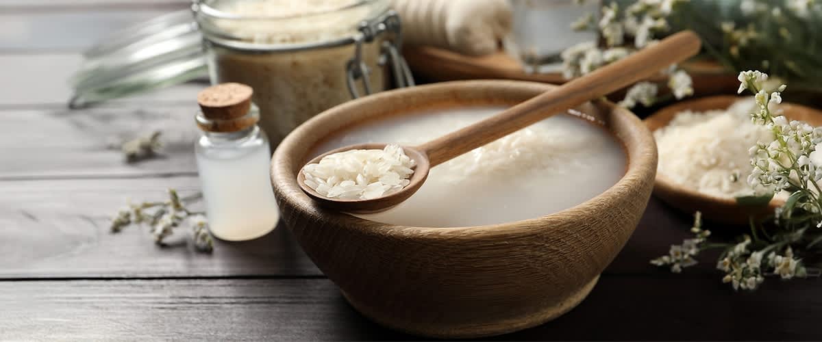 Rižina voda u drvenoj zdjeli sa žlicom i staklenom posudom