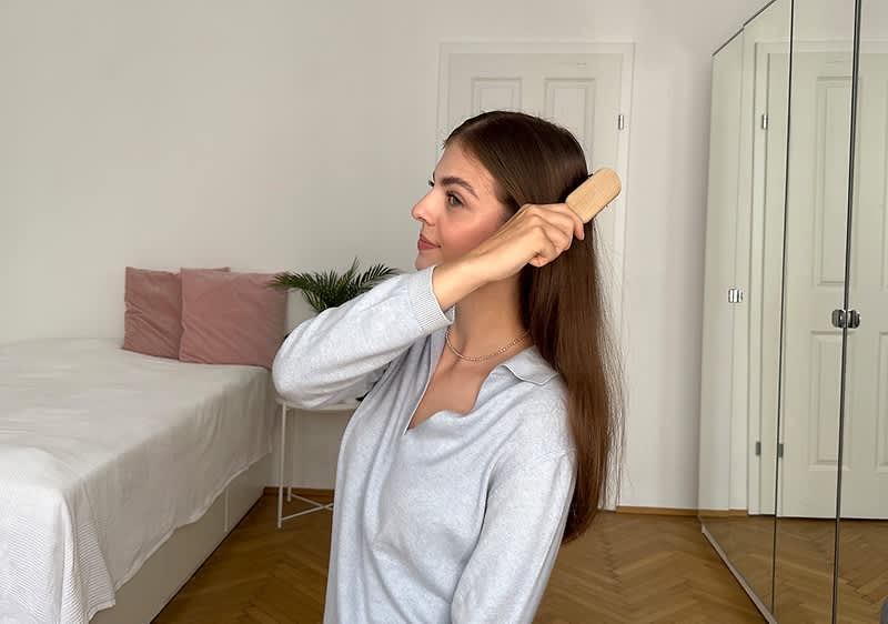 Žena češlja dugu kosu četkom