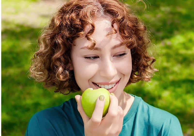 Nasmijana žena s jabukom, u rukama