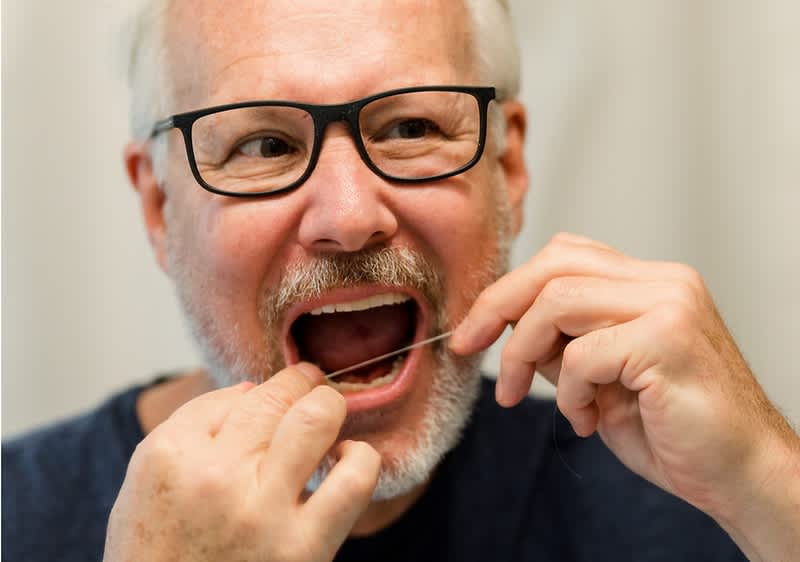 Muškarac čisti zube zubnim koncem