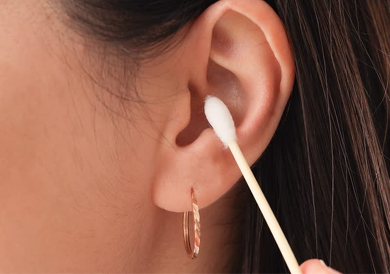 Djevojka čisti uho štapićem za uši