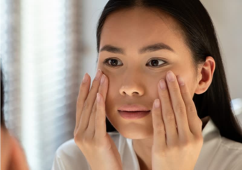 djevojka promatra svoje lice u ogledalu