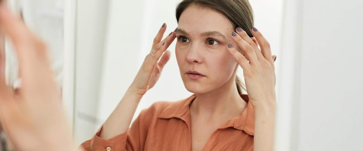 Žena promatra svoje lice u ogledalu