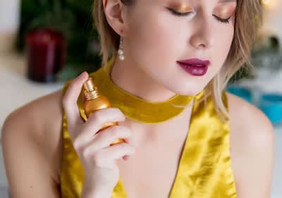 djevojka u žutoj haljini nanosi parfem na vrat