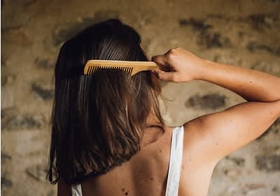 Djevojka snimljena s leđa čelja četkom svoju kosu