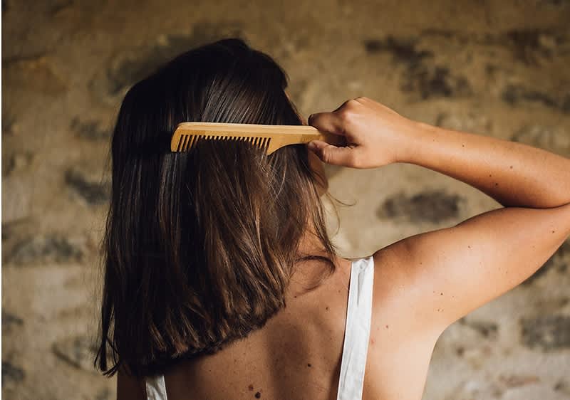 Djevojka snimljena s leđa čelja četkom svoju kosu