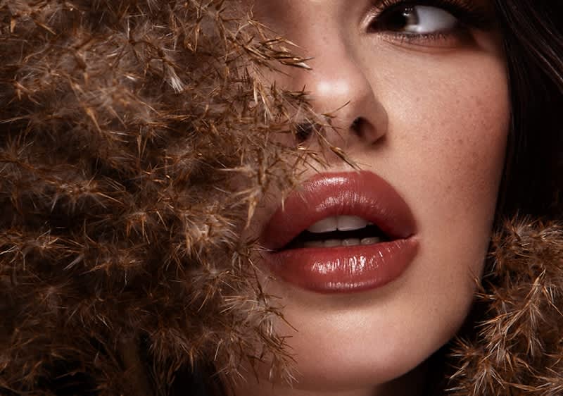 Djevojka kovrčave kose sa smeđim ružem na usnama