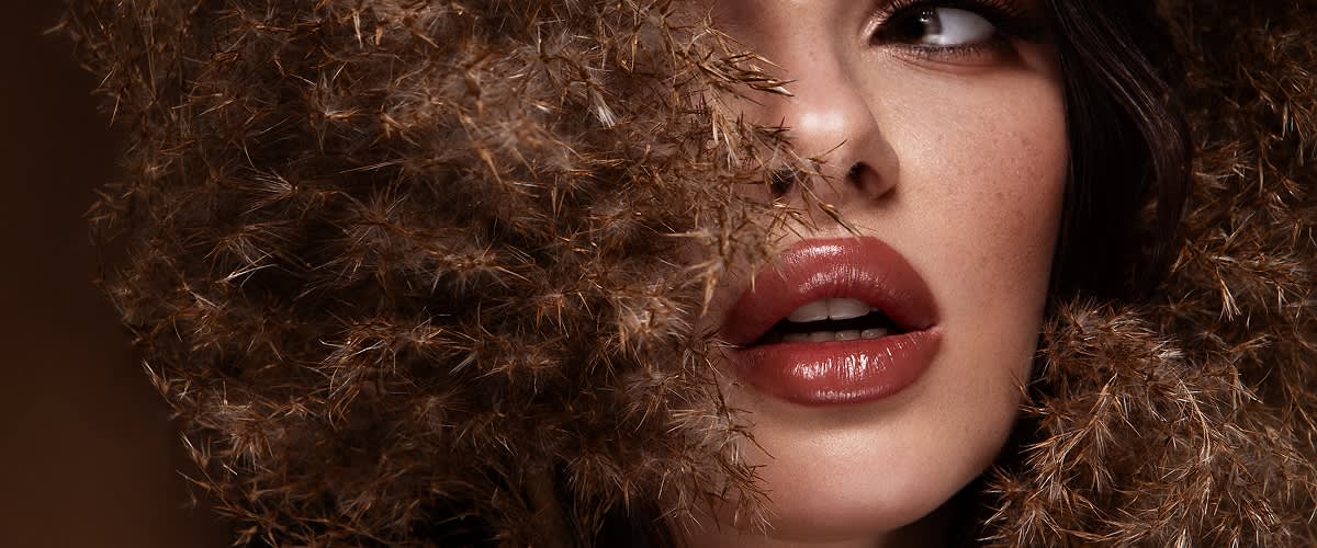 Djevojka kovrčave kose sa smeđim ružem na usnama