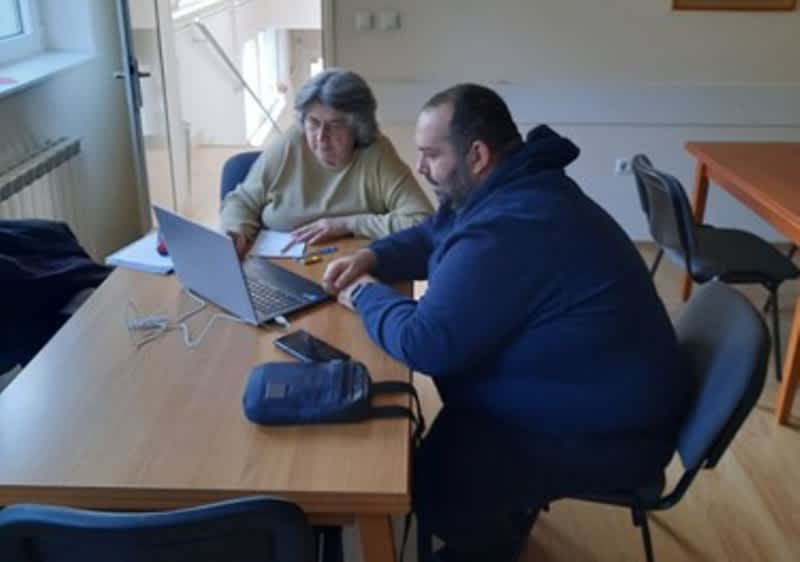 Marko i žena sjede za stolom i gledaju u laptop