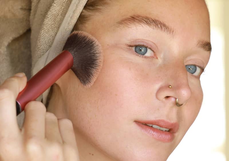 Djevojka kistom nanosi make up na obraze