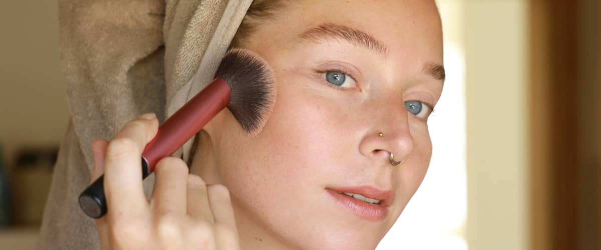 Djevojka kistom nanosi make up na obraze