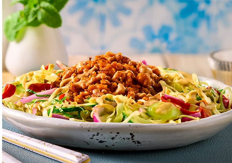 Tanjur veganskog kebaba s karameliziranim kikirikijem i umakom od sjeckanog kikirikija, vidljive kriške krastavca, čilija i crvenog luka