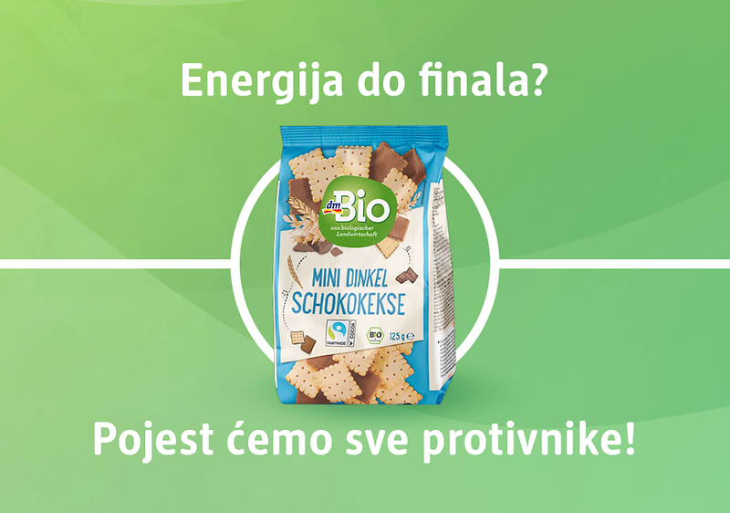 Slika koja prikazuje pakiranje dmBio mini čokoladni keksa na zelenoj podlozi koja simbolizira nogometni teren
