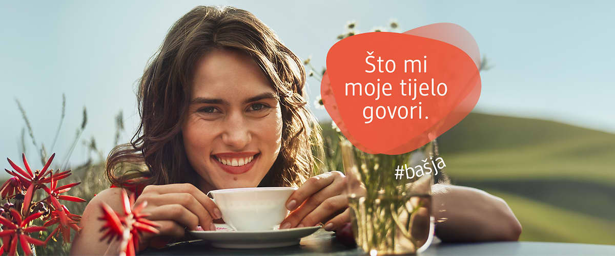 Slika žene koja se smije i pije čaj uz poruku što mi moje tijelo govori
