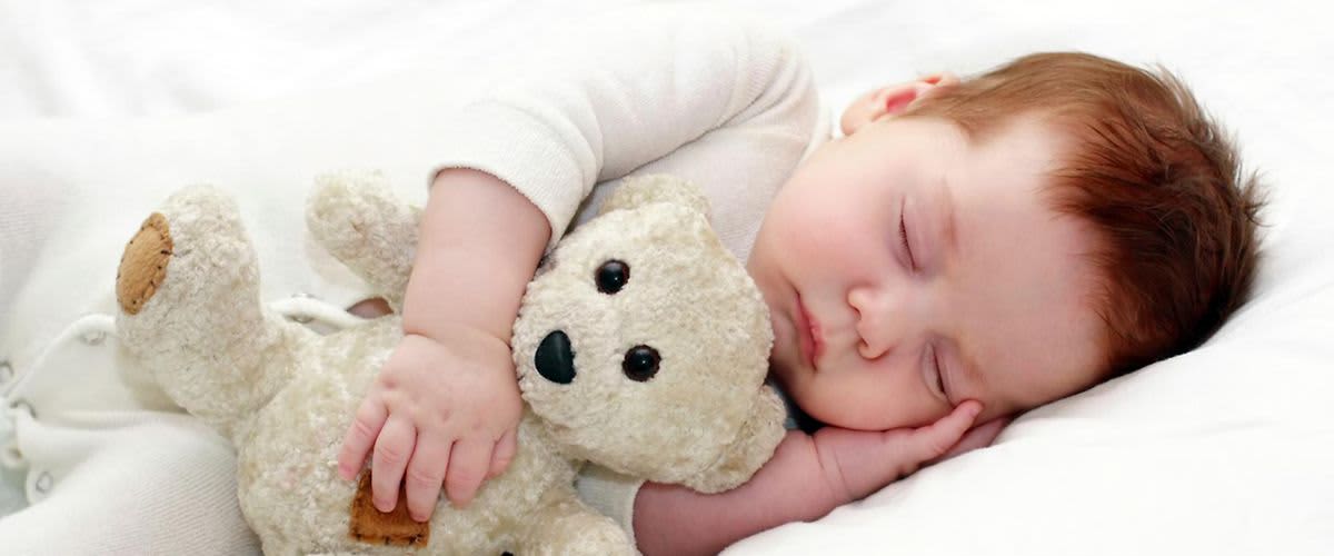 beba koja spava u krevetu s medvjedićem