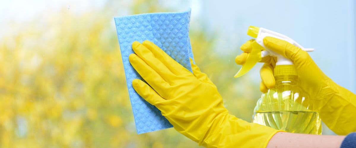 Žena koja u žutim gumenim rukavicama pere prozore