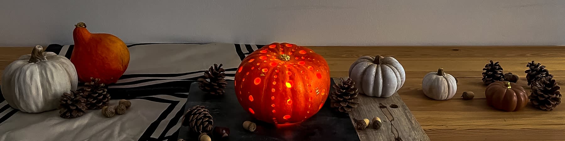 Faragott tök világítással és fenyőtobozokkal körülvéve