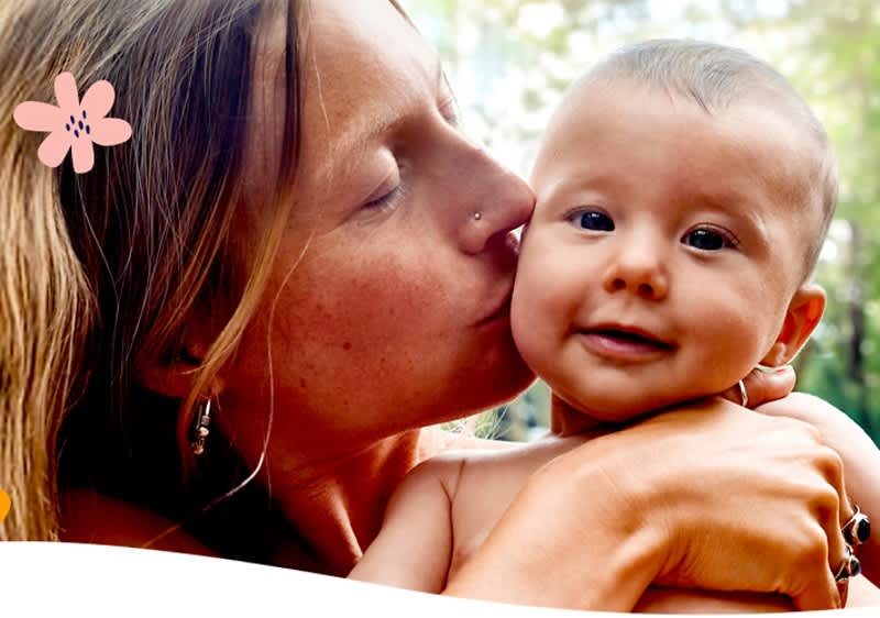 Mutter mit Baby im Freien umgeben von Pflanzen und Blumen
