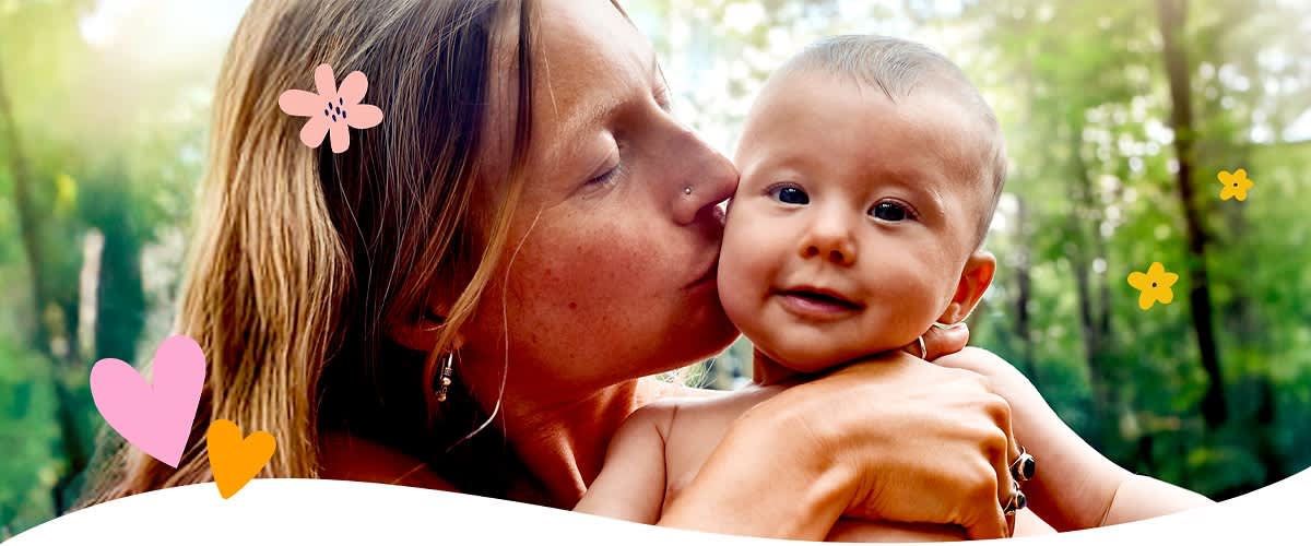 Mutter mit Baby im Freien umgeben von Pflanzen und Blumen