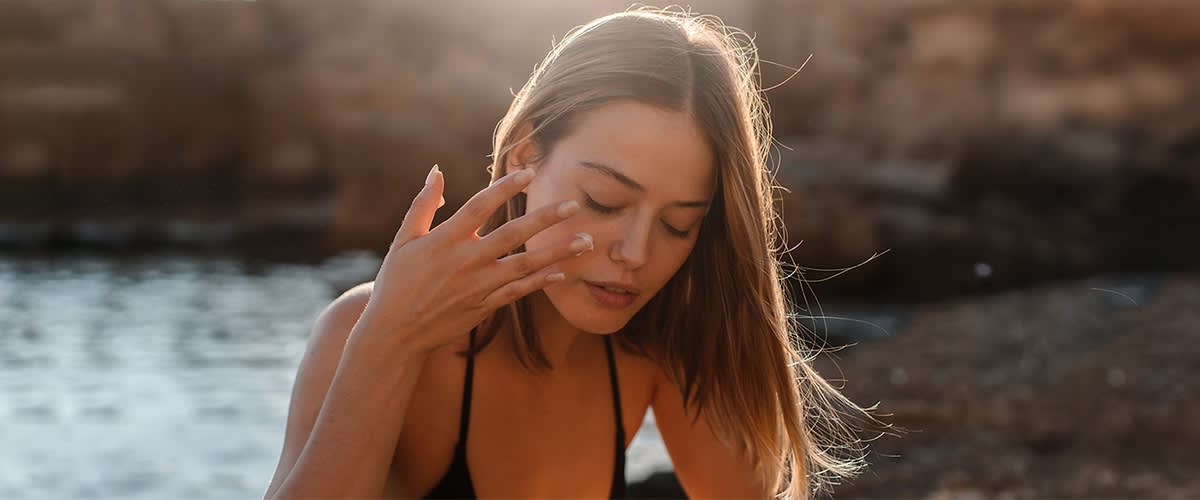 Nő a tengerparton krémezi az arcát