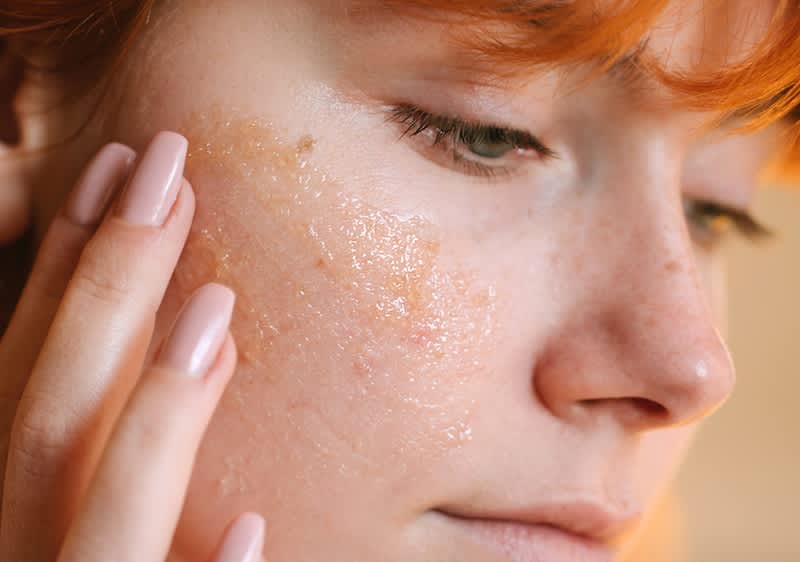 Egy vörös hajú nő végigsimítja az arcát a kezével