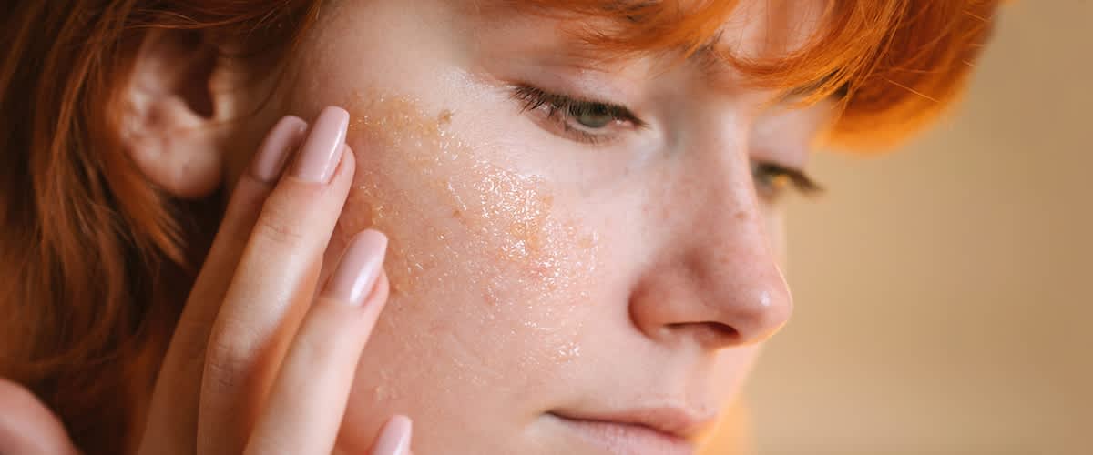 Egy vörös hajú nő végigsimítja az arcát a kezével