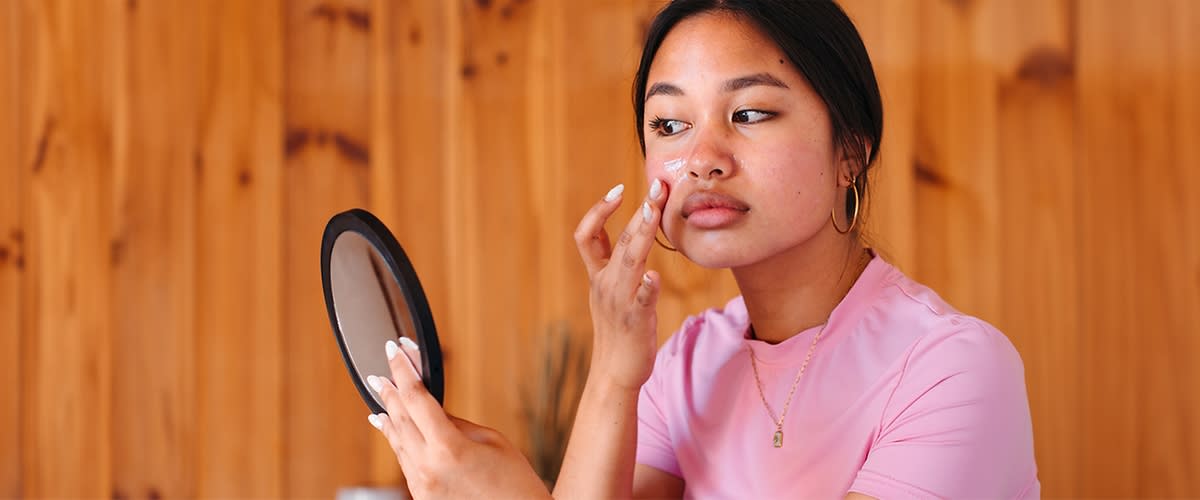 Egy nő krémmel keni be az arcát