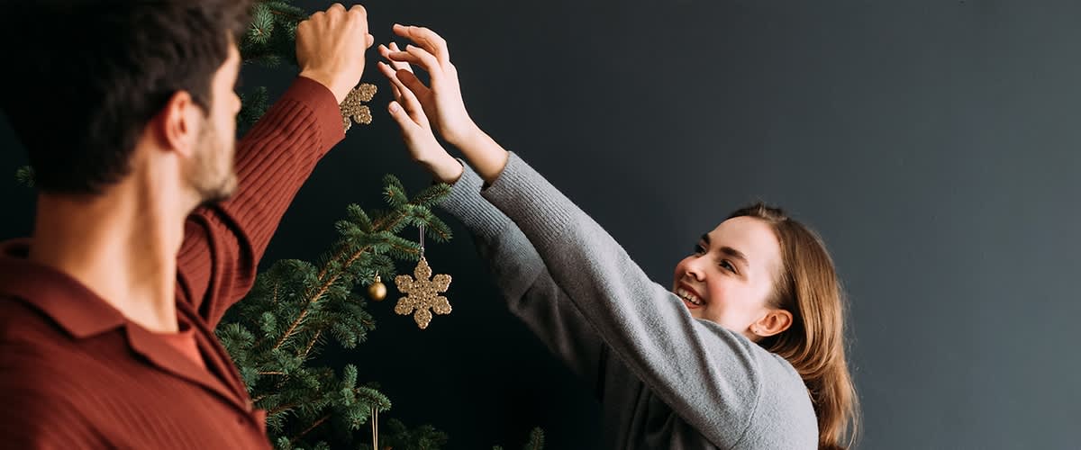 Egy nő és egy férfi karácsonyfát díszít