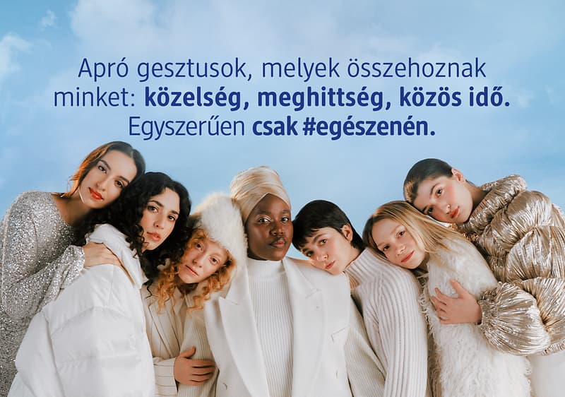 Csoportos ölelés téli ruhákban felhős háttér előtt