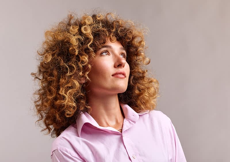 Göndör hajú nő rózsaszín ingben