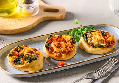 Vegetáriánus pizzatekercsek tányéron bazsalikommal és evőeszközzel