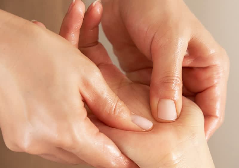 Egy női kéz masszírozza egy másik női kéz tenyerét