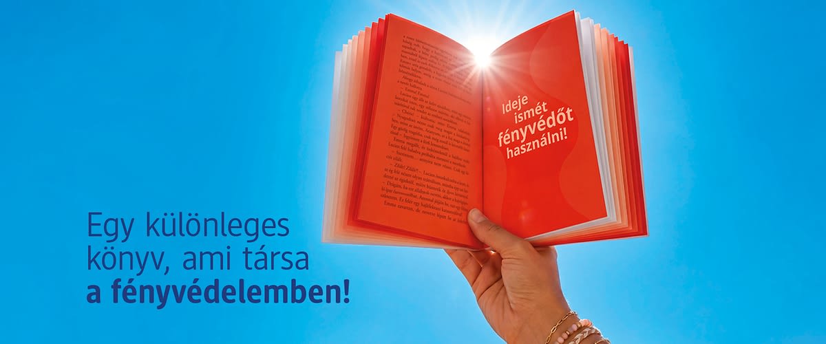 Közeli kép egy kézben tartott, kinyitott piros könyvről, melyből fény sugárzik, kék háttérrel és magyar szöveggel</p>