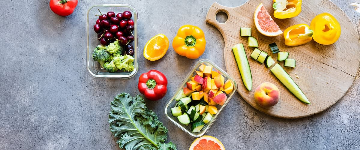 Üveg dobozok és vágódeszka zöldségekkel és gyümölcsökkel: cseresznye, brokkoli, paprika, uborka, barack, narancs, grépfrút, kelkáposzta