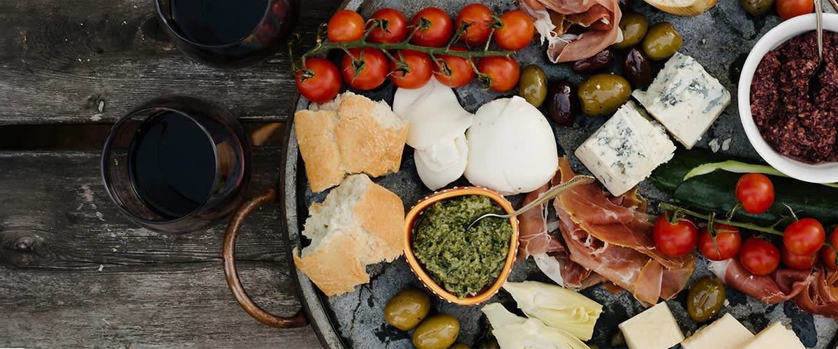 Tapasztalt sajttál olívával, paradicsommal, bagettel és pesto mártással